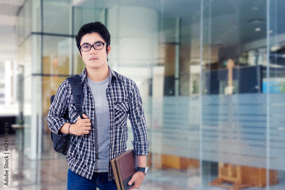 Obraz premium Photo of serious young male student standing in front of glass door