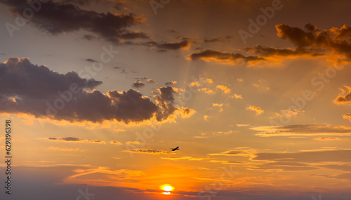 Beautiful sunset sky with spectacular clouds. Airplane silhouette taking of in front of the sun. © Dragoș Asaftei