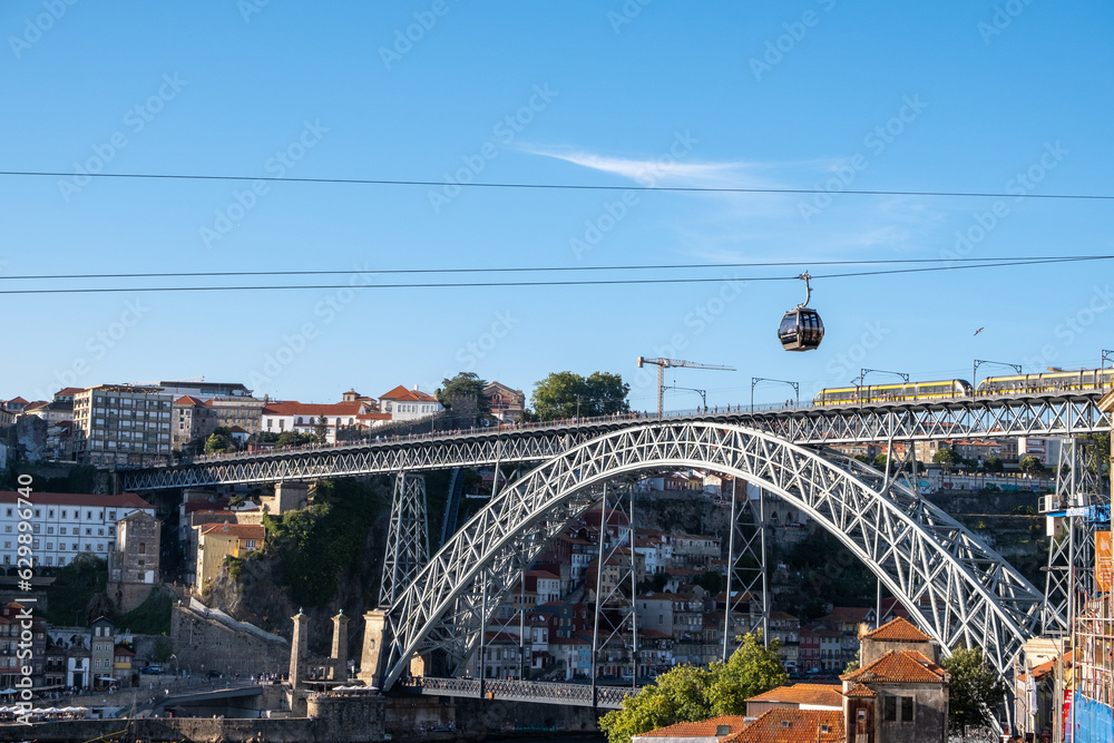 Fototapeta premium Imagen de uno de los famosos puentes de la ciudad portuguesa de Oporto con el teleférico cruzando el río Duero por las alturas.