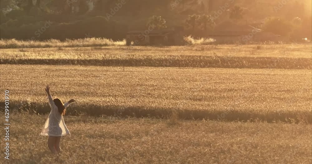 Chica andando por atardecer por el campo de trigo