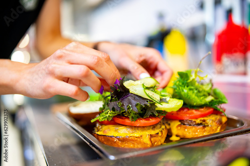 woman chef hand cooking burger with vegetables and meat on restaurant kitchen