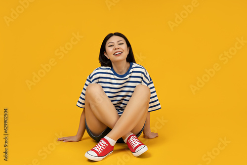 Beautiful Asian girl in stylish clothes sitting on the floor photo