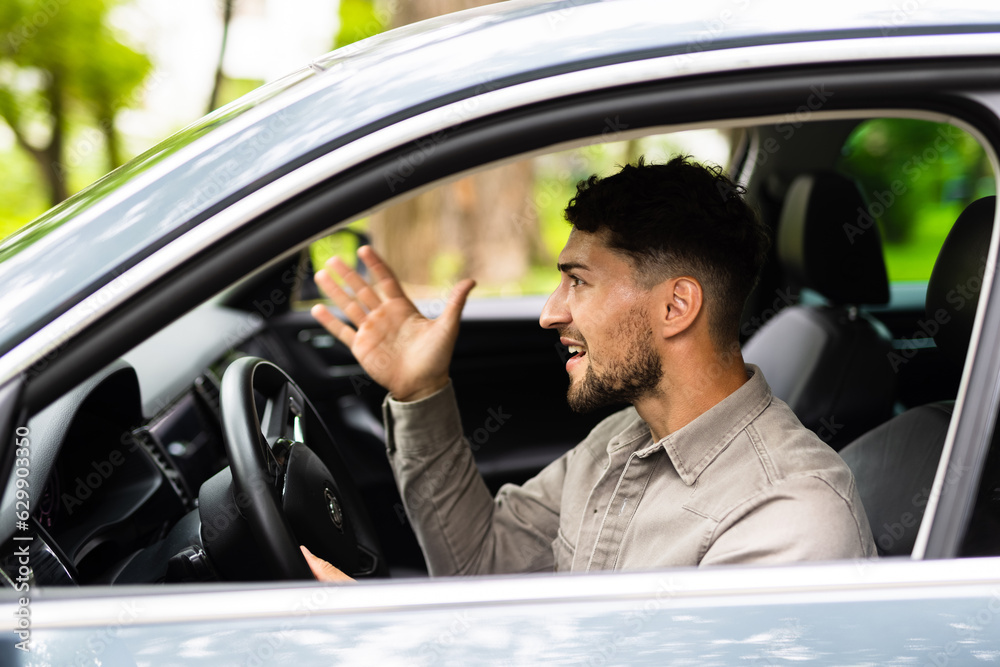 Young handsome man driving car with furious expression at street