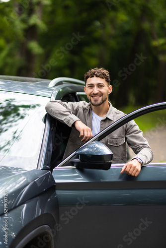 Smiling man standing next to his car on the street