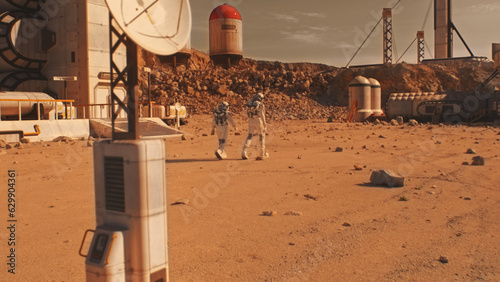 Two astronauts, scientists in spacesuits walk on Mars surface. Research station, colony or scientific base on red planet. Exploring space mission. Futuristic colonization and exploration concept. photo