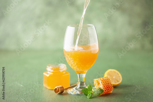 Honey craft drink medovukha in pint glass on a green background. Russia craft alcohol photo