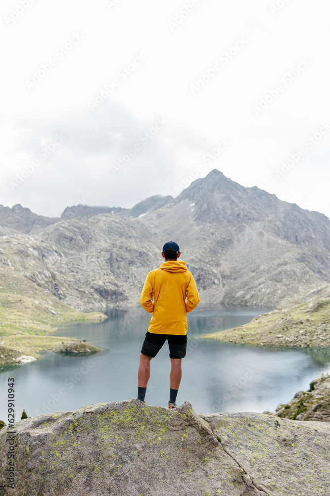 Fototapeta premium Young man standing on a rock with mountain background