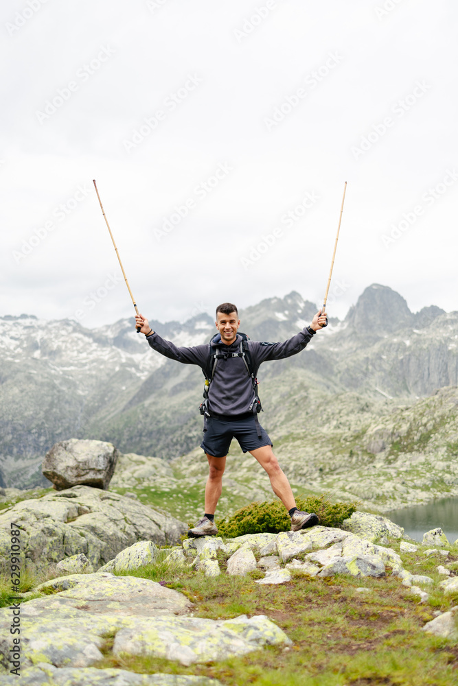Obraz premium Young man standing on a rock with mountain background