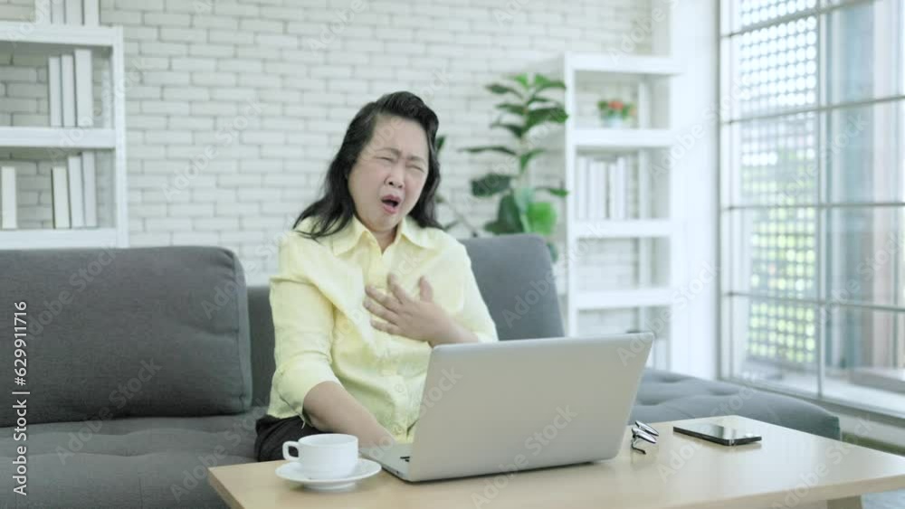 young asian female daughter watching and helping old asian woman working with laptop and having chest pain or heart attack young asian female daughter watching and helping old asian woman working with laptop and having chest pain or heart attack