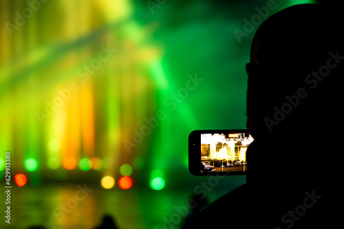 Man recording a light and water show on his smartphone