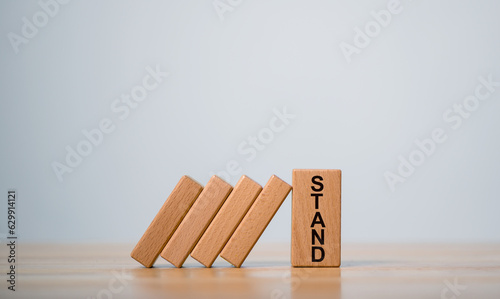 Wooden block stand stopping domino business crisis effect  Money coins heap still balance and stop the falling domino  financial stability concept