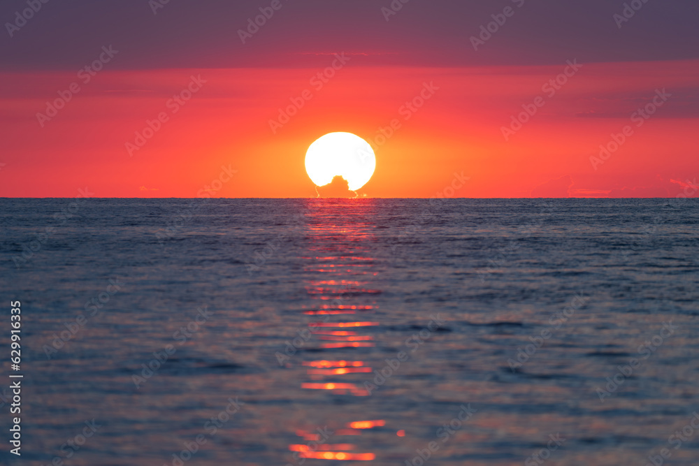The red sun sets in the sea