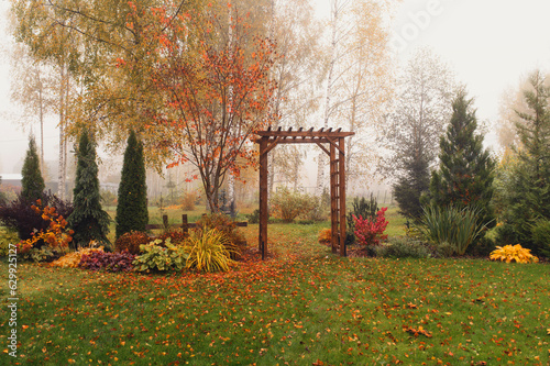 Leinwand Poster autumn garden view in october with wooden archway