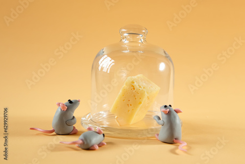 Little plasticine gray mice look at an inaccessible piece of cheese.