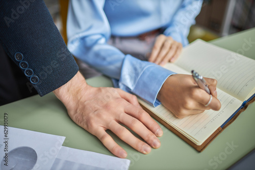 Canvas Print Closeup of male boss leaning over young woman at desk in office, workplace haras