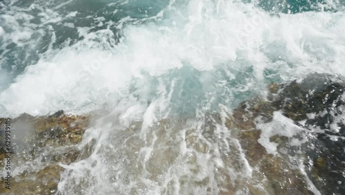 From a top view in slow motion, we observe how the wave crashes onto the rocky coastline and recedes back into the sea. photo