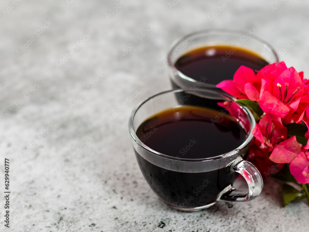 Fototapeta premium High angle shot of black coffee cups with pink flowers and copy space on the side.