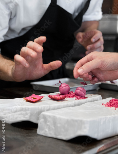 Vertical photo with two hands of cooks preparing a gastronomic dish