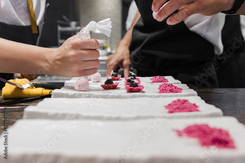 Photo of the hands of two chefs preparing together a dish in a gastronomic restaurant.
