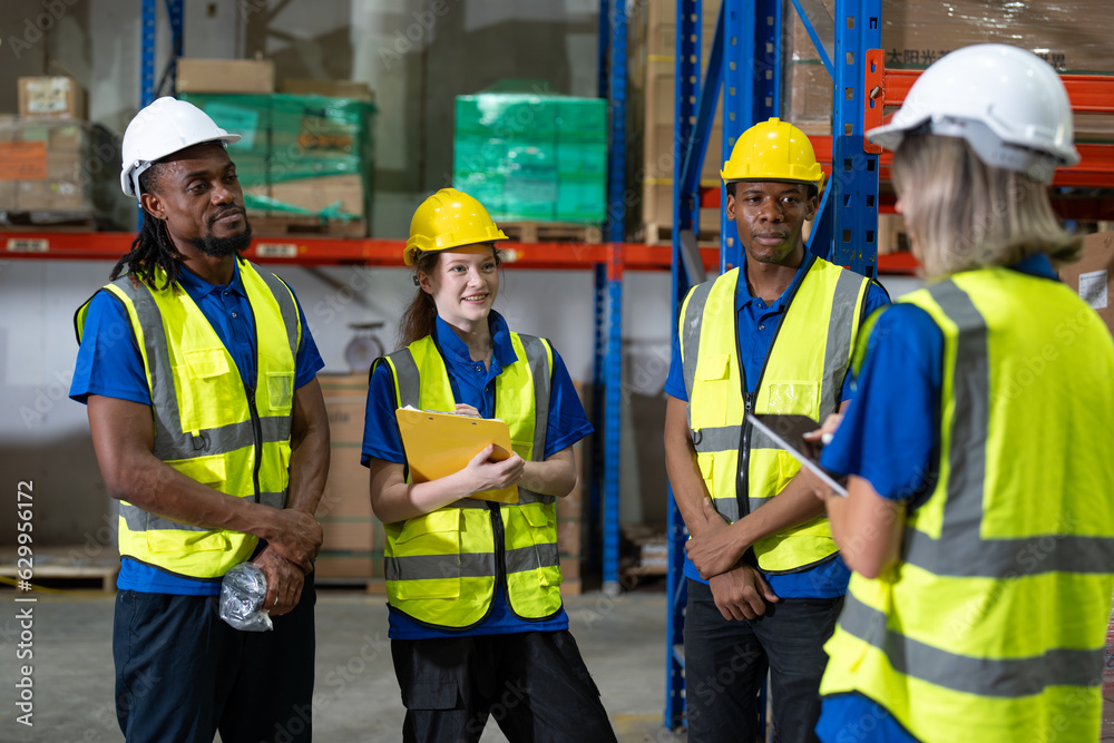 Man and woman warehouse worker team wearing vest and helmet safety meeting at storage factory. Logistics, Distribution Center concept. Man and woman warehouse worker team wearing vest and helmet safety meeting at storage factory. Logistics, Distribution Center concept.