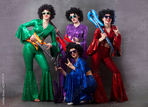 Group of girls in disco style with toy guitars. Vintage disco group for women.