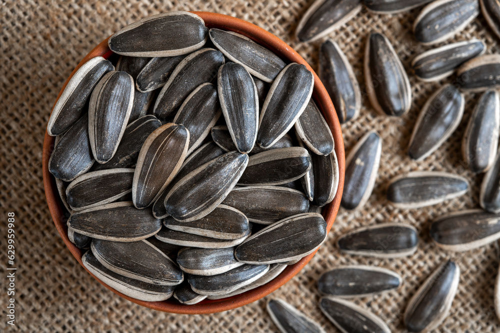 Black sunflower seeds in a bowl on burlap sack Black sunflower seeds in a bowl on burlap sack