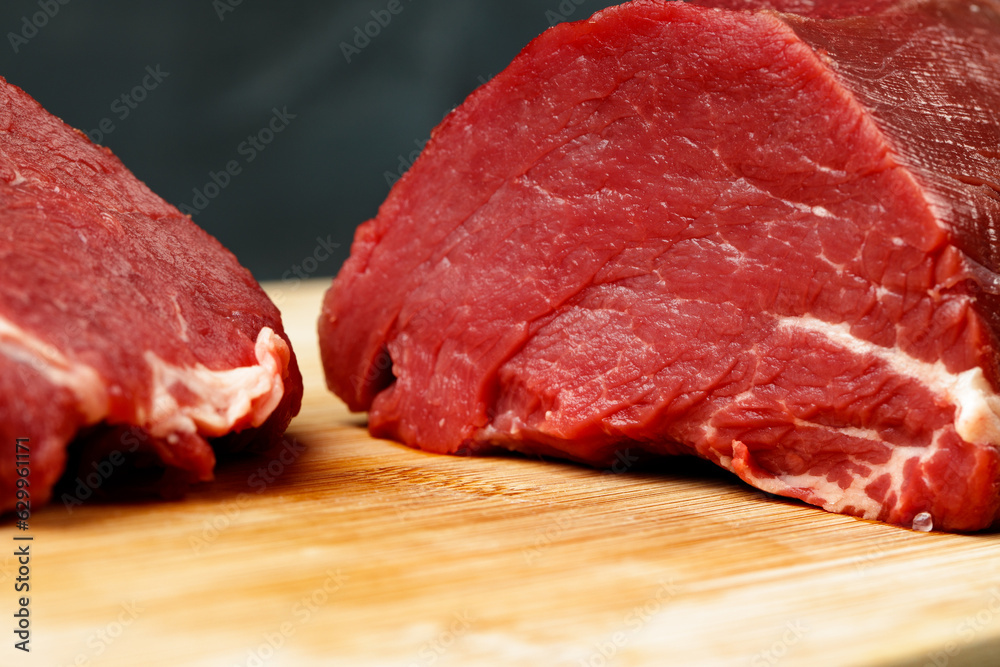 Slice of raw beef fillet on wooden board