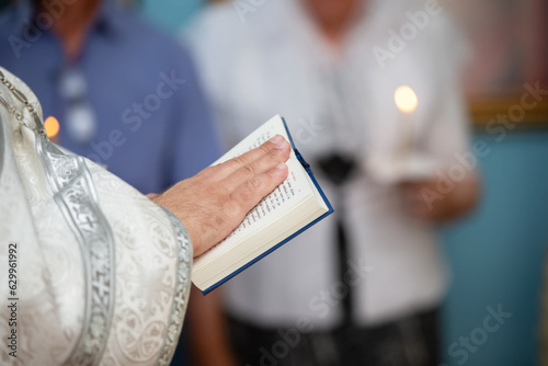 The hands of an Orthodox priest in a cassock hold a bible.