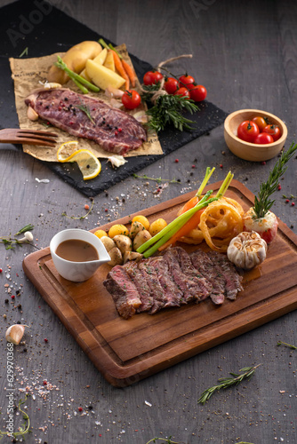 Grilled rib eye steak with pepper sauce on wooden background