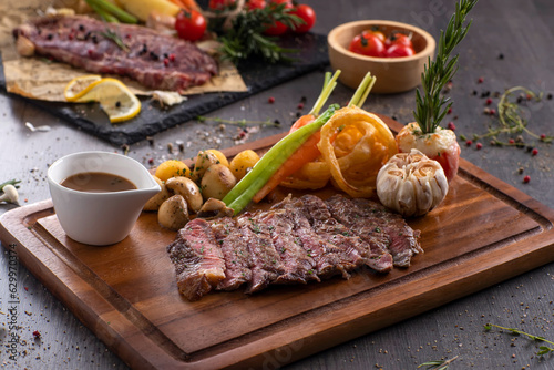 Grilled rib eye steak with pepper sauce on wooden background