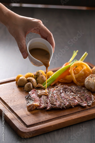 Grilled rib eye steak with pepper sauce on wooden background