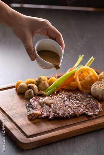 Grilled rib eye steak with pepper sauce on wooden background