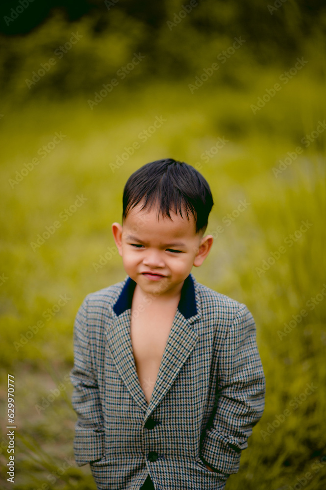 cute little boy A well-dressed boy in a suit in a backyard with a lawn and looking for something interesting. cute little boy A well-dressed boy in a suit in a backyard with a lawn and looking for something interesting.