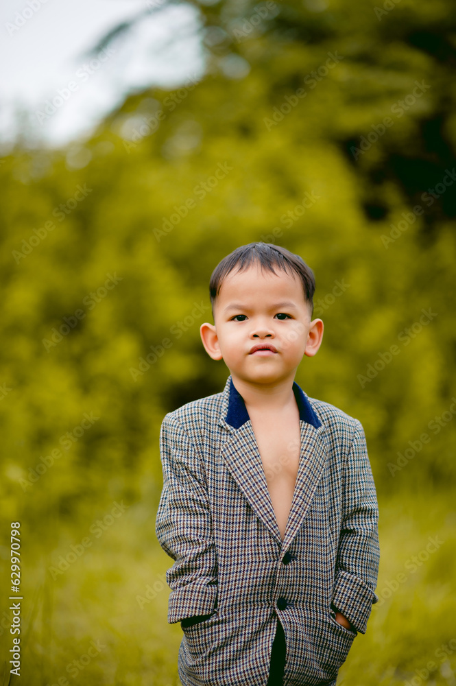 cute little boy A well-dressed boy in a suit in a backyard with a lawn and looking for something interesting. cute little boy A well-dressed boy in a suit in a backyard with a lawn and looking for something interesting.