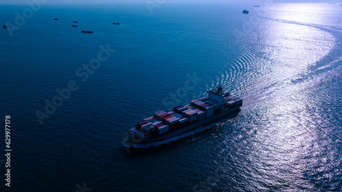 night process blue tone of cargo container ship sailing full speed in sea to import export goods and distributing products to dealer and consumers worldwide, by container ship Transport business © SHUTTER DIN