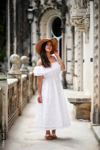 Asian woman wearing a hat and white dress.