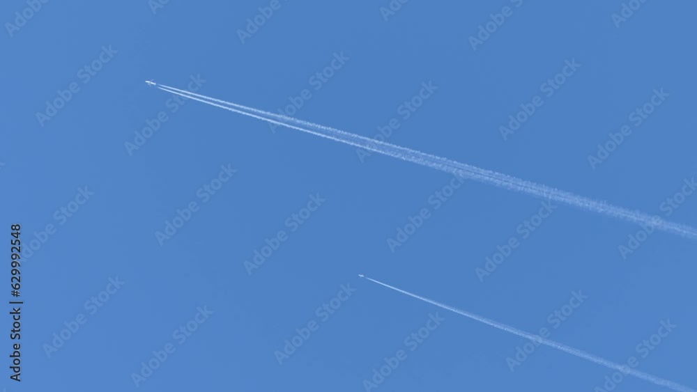 Two planes flying in parallel against the background of a blue sky and leaving a trails of condensation clouds in the form of white lines - real time. Two planes flying in parallel against the background of a blue sky and leaving a trails of condensation clouds in the form of white lines - real time.