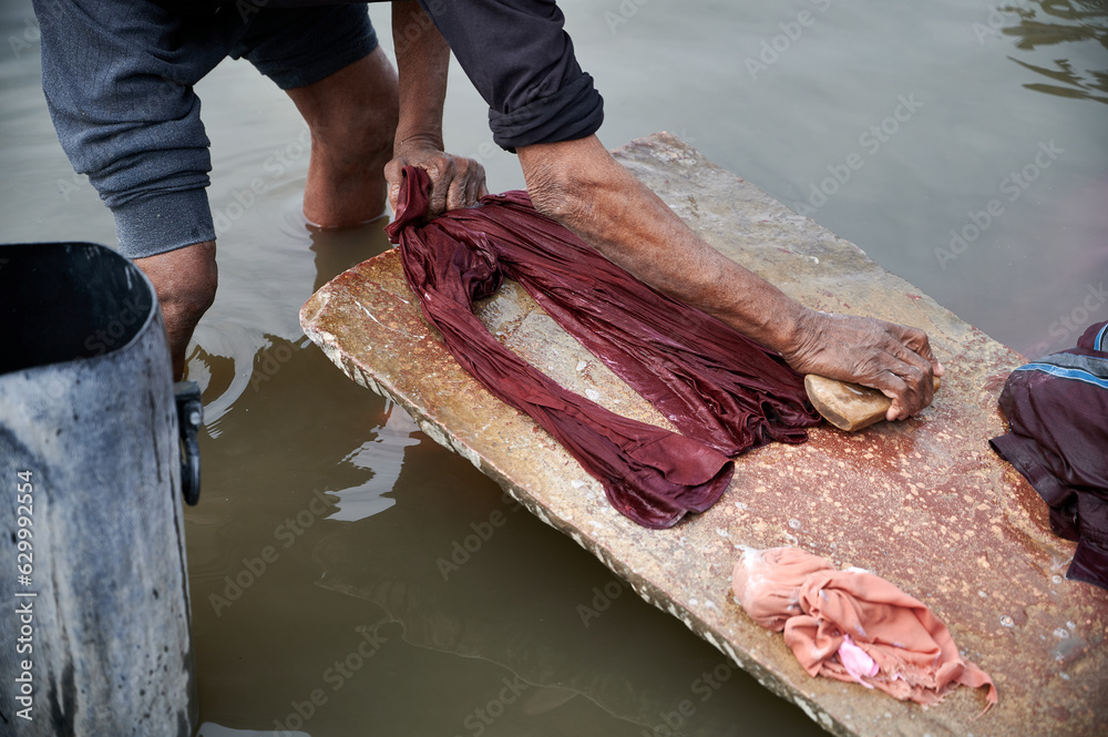 laundry workers at the Jamuna River in Agra near the famous Taj Mahal. Lots of colorful dirty clothes washed in chemicals for very little pay