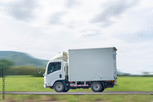 Side view of a small truck driving on a country road, truck running on the road, small truck on the road.