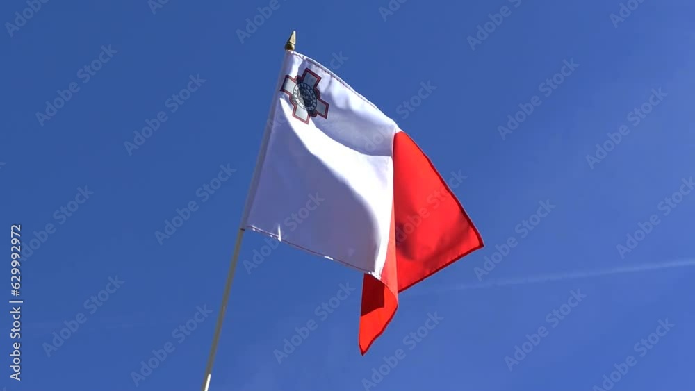 The Maltese flag waving in the wind in the blue sky