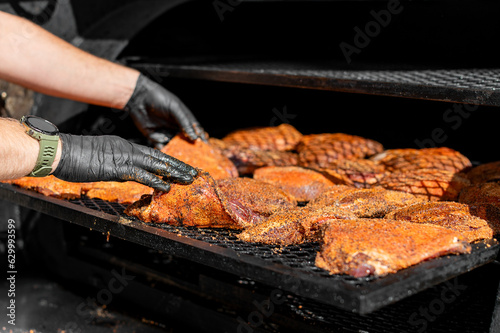 Chef hand cooking grilled beef meat in BBQ smoker.
