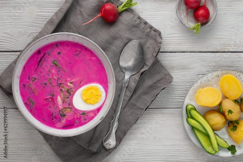 Chłodnik, Šaltibarščiai is traditional lithuanian, polish beet soup. Cold summer soup of beetroot, kefir, cucumbers, eggs, dill and potatoes in a bowl on a wood table. Summer Healthy food. Top view photo