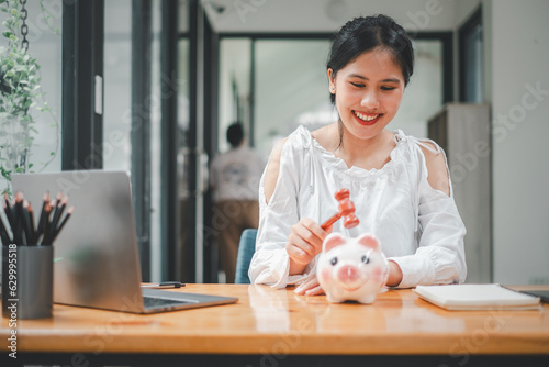 Woman hand holding a hammer which is raised above a piggy bank, with a shocked and apprehensive facial expression. photo