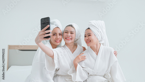 Group of beautiful women in bathrobes taking selfies with mobile phones.