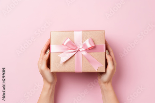 Overhead view of a woman holding a pink gift box with pink bow