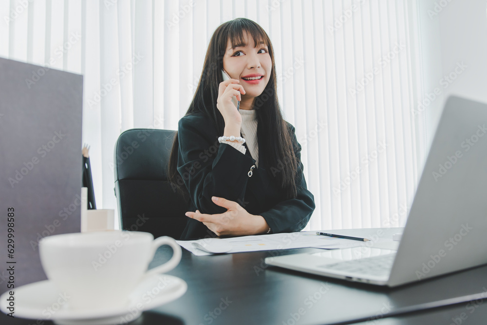 woman talking on the mobile phone and smiling while sitting at her working place in office. woman talking on the mobile phone and smiling while sitting at her working place in office.