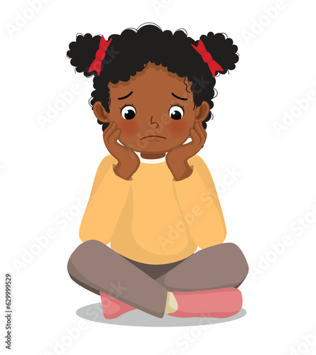 Sad little African girl sitting on the floor with her chin resting on her hands