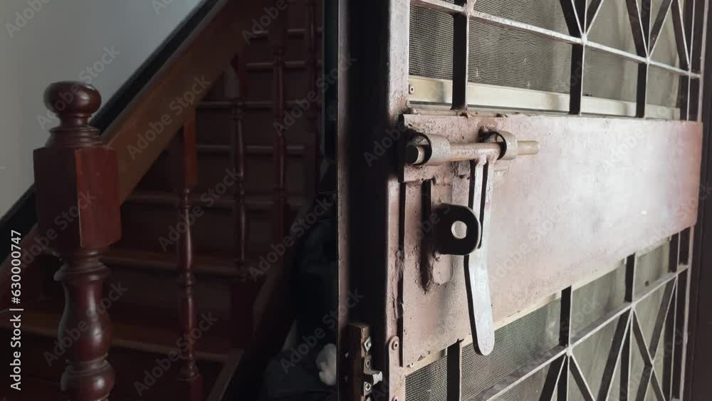 Opening old metal door at home with wooden stairs nearby interior view, Thailand Opening old metal door at home with wooden stairs nearby interior view, Thailand