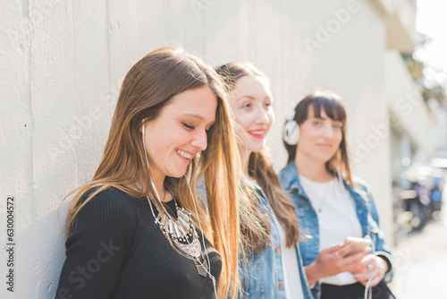Three beautiful young women millennials listening music