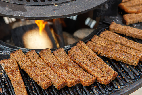 Pieces of black rye bread, grilled, lie on the grill.